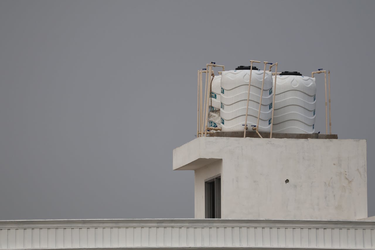 White water tanks on a rooftop with architectural design, under a gray sky.